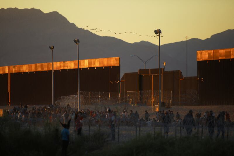 Migrants gather near the border wall separating the US and Mexico. Reuters