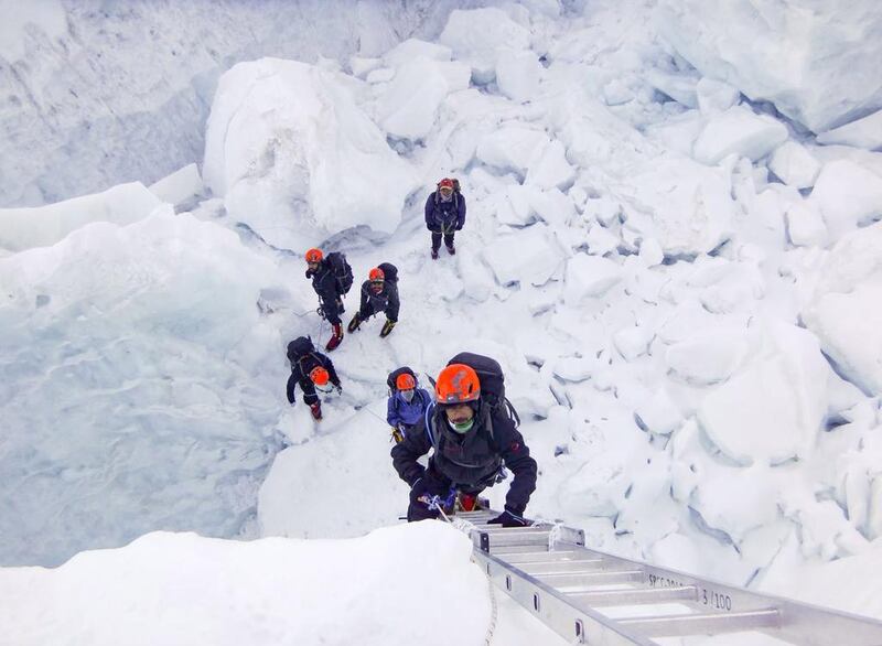 Members of the Armed Forces climb a ladder during an Everest expedition.