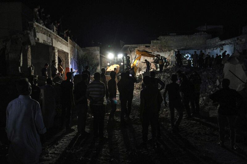 People watch as members of the Syrian Civil Defence, also known as the "White Helmets", attempt to clear debris as they search for bodies or survivors in a collapsed building following a reported government air strike in the village of Saraqib in Syria's northwestern Idlib province.  AFP