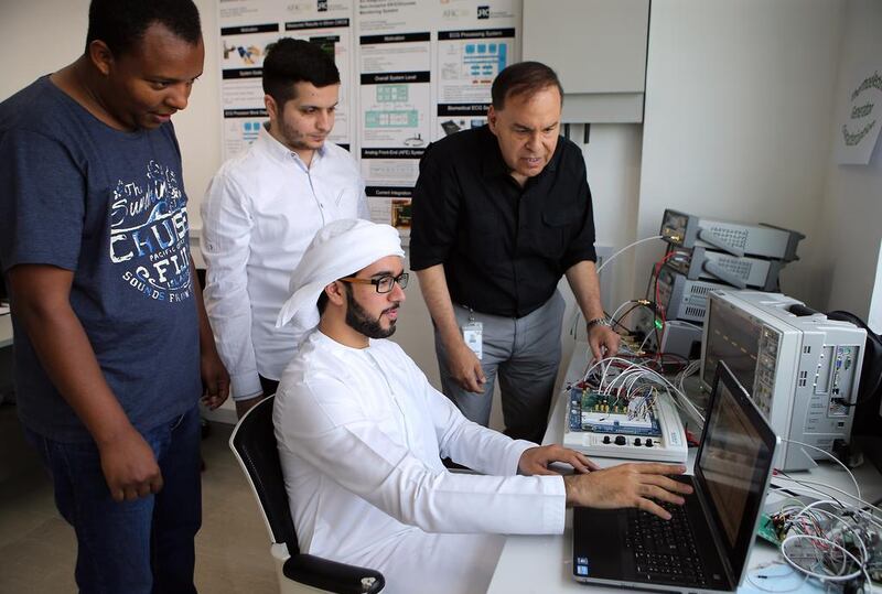 The director of the Khalifa University semiconductor research centre, Prof Mohammed Ismail (in black), and his team members, from left, Jonatan Kifle, Mohammad Al Hawari, and Saif Al Junaibi, look at results for their new device.  Ravindranath K / The National