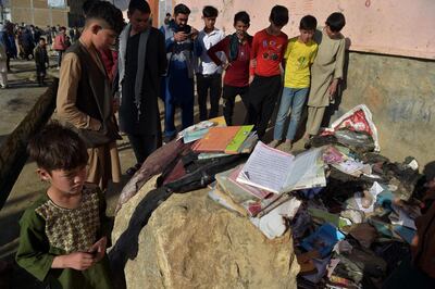 EDITORS NOTE: Graphic content / Onlookers stand next to the backpacks and books of victims following multiple blasts outside a girls' school in Dasht-e-Barchi on the outskirts of Kabul on May 9, 2021, as the death toll has risen to 50, the interior ministry said.  / AFP / WAKIL KOHSAR
