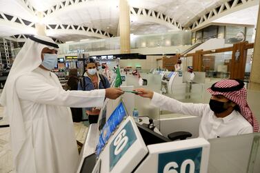 A Saudi man wearing a face mask gets his passport from a Saudi Immigration officer, at the King Khalid International Airport, after Saudi authorities lifted the travel ban on its citizens after fourteen months due to coronavirus disease Covid-19 restrictions, in Riyadh, Saudi Arabia, May 16, 2021. Reuters