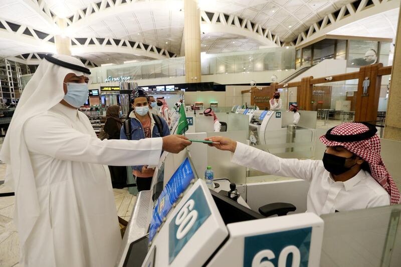 A Saudi man wearing a face mask gets his passport from a Saudi Immigration officer, at the King Khalid International Airport, after Saudi authorities lifted the travel ban on its citizens after fourteen months due to coronavirus disease (COVID-19) restrictions, in Riyadh, Saudi Arabia, May 16, 2021. REUTERS/Ahmed Yosri