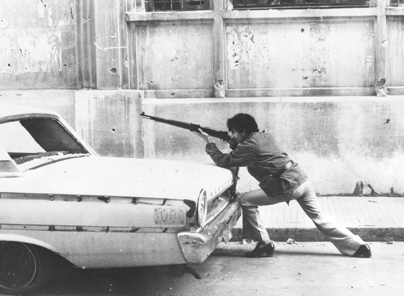December 1975:  A man aiming a rifle over the back of a car on a street in Beirut, Lebanon during the country's civil war.  (Photo by Keystone/Getty Images)