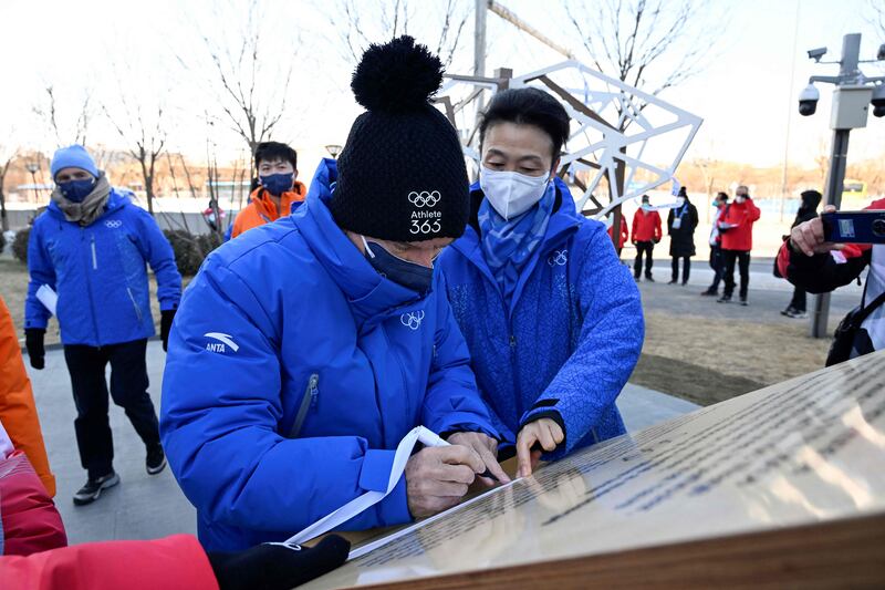 Thomas Bach, President of the International Olympic Committee, signs his name as he visits the Beijing 2022 Winter Olympic Games village. AFP