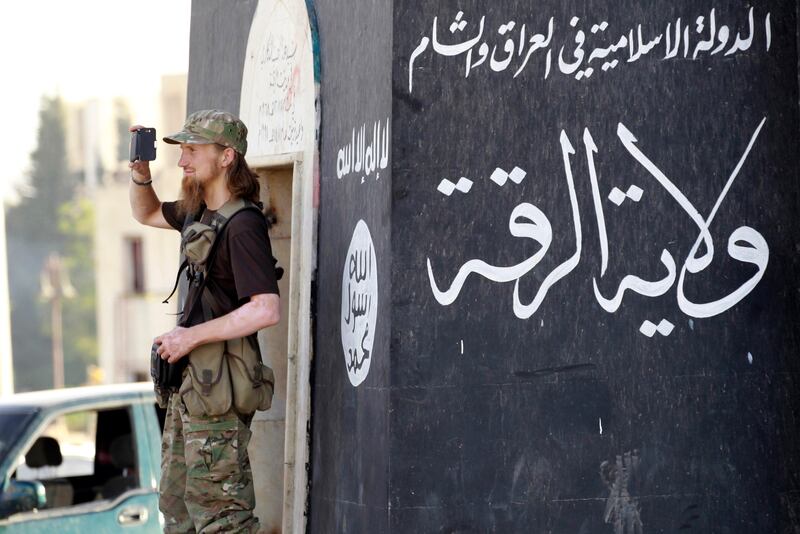 A fighter films his fellow militants taking part in a military parade in Raqqa province in June 2014.