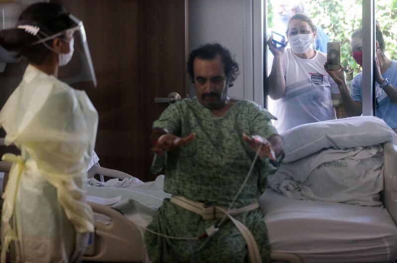 Family members watch from outside COVID-19 patient Isaias Perez Yanez's room, as he is assessed by occupational therapist Jaclyn Lien in the Progressive Care Unit (PCU) at Sharp Coronado Hospital, California. Getty Images/AFP