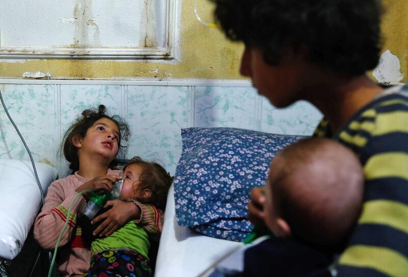 TOPSHOT - A Syrian girl holds an oxygen mask over the face of an infant at a make-shift hospital following a reported gas attack on the rebel-held besieged town of Douma in the eastern Ghouta region on the outskirts of the capital Damascus on January 22, 2018. 
At least 21 cases of suffocation, including children, were reported in Syria in a town in eastern Ghouta, a beleaguered rebel enclave east of Damascus, an NGO accusing the regime of carrying out a new chemical attack said. Since the beginning of the war in Syria in 2011, the government of Bashar al-Assad has been repeatedly accused by UN investigators of using chlorine gas or sarin gas in sometimes lethal chemical attacks.
 / AFP PHOTO / HASAN MOHAMED