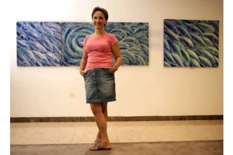 Boryana Korcheva in front of her works on display at the Fujairah Tennis Club. The exhibition, Whoosh!, was named after her triptych of fish caught in a whirl of motion and colour.