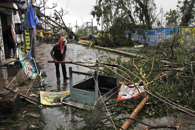 An Indian man salvages a table stuck in uprooted trees fallen during Cyclone Phailin on a road in Berhampur, India. AP Photo/Bikas Das