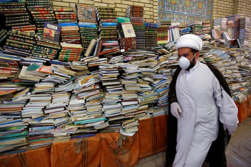 A Shi'ite Muslim man wears a protective face mask, following the outbreak of the coronavirus disease (COVID-19), as he walks next to religious books during the holy month of Ramadan in Najaf, Iraq, May 16, 2020. REUTERS/Alaa Al-Marjani