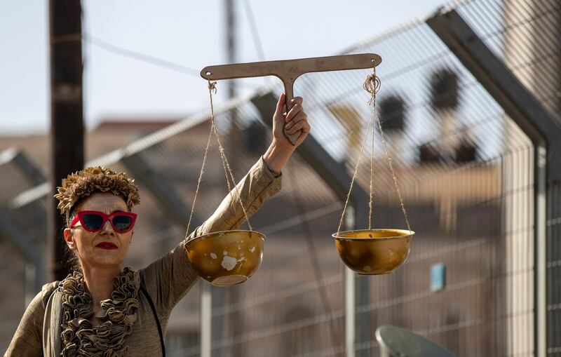 A woman holds the Scales of Justice as protests call for an end to Mr Netanyahu's leadership. EPA