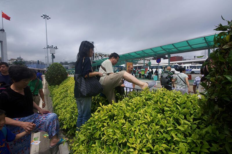 Commuters climb over bushes and railings in the middle of a main road after underground passageways were blocked by floodwaters brought on by Typhoon Hato in Macau. Anthony Wallace / AFP