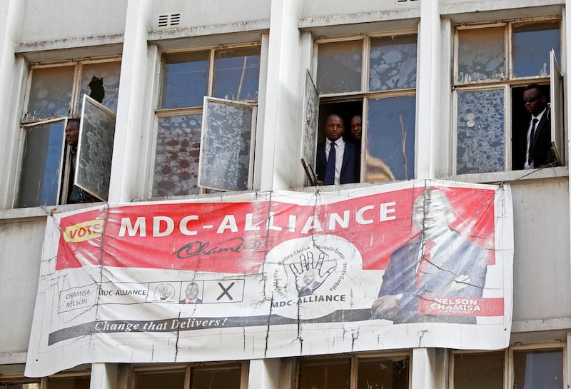 People peer through the windows of the headquarters of the opposition Movement for Democratic Change (MDC) party. Reuters