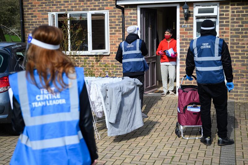 A woman speaks with volunteers as they deliver Covid-19 test kits to the doors of residents near Muswell Hill in London. Over the weekend, the Haringey and Barnet borough councils began door-to-door distribution of test kits after a local resident tested positive for the coronavirus variant first identified in Brazil. Getty Images