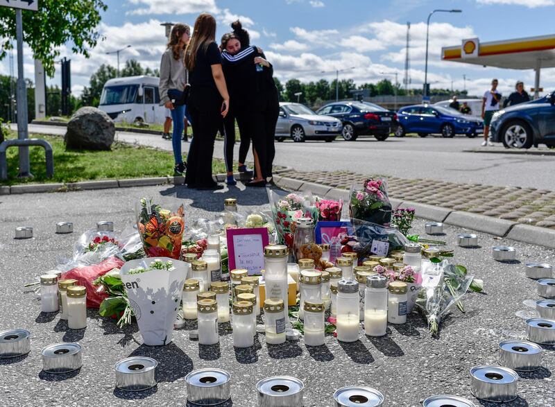 People gather near to where a twelve-year-old girl was shot and killed near a petrol station in Botkyrka, south of Stockholm, Sweden, Monday Aug. 3, 2020. (Stina Stjernkvist/TT via AP)