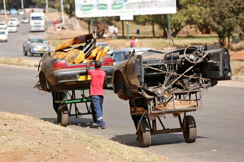 epa07608445 Men pull and push carts laden with half pieces of a what was once a motor vehicle in Harare, Zimbabwe, 28 May 2019.The vehicle will be stripped apart and the scrap metal to be sold to earn a living. Zimbabweans are facing economic challenges as prices of almost everything rising everyday.  EPA/AARON UFUMELI