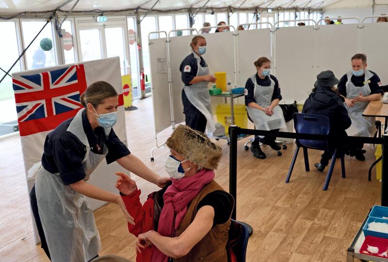 A patient receives an injection of the Oxford/AstraZeneca Covid-19 vaccine by Royal Navy medics at a vaccination centre set up at Bath racecourse in Bath, southwest England on January 27, 2021. Over 30 new coronavirus vaccination centres were set to open around England this week as Britain's largest ever innoculation programme continued to gain pace.  / AFP / Adrian DENNIS
