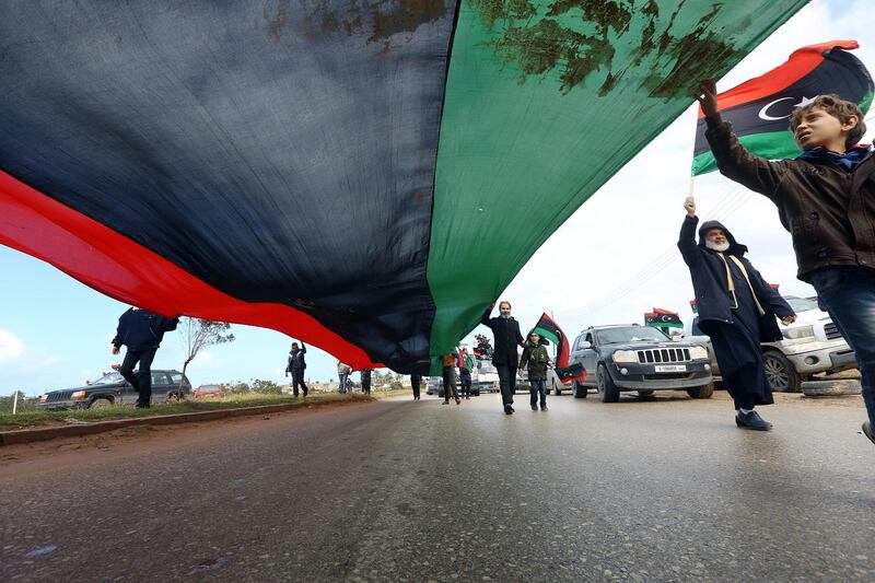 Libyans carry a giant national flag in the capital Tripoli during a celebration to mark the the upcoming eight anniversary of the Libyan revolution which toppled Muammar Qaddafi. AFP