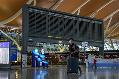 A passenger pushes his luggage past a blank flights information board at Pudong International Airport in Shanghai, China, Sunday, July 25, 2021.  Airline flights were canceled in eastern China as Typhoon In-fa churned toward the mainland. AP