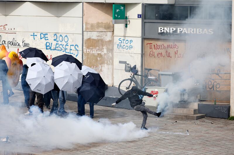 Youths kick tear gas grenades during a demonstration in Nantes, western France. AP