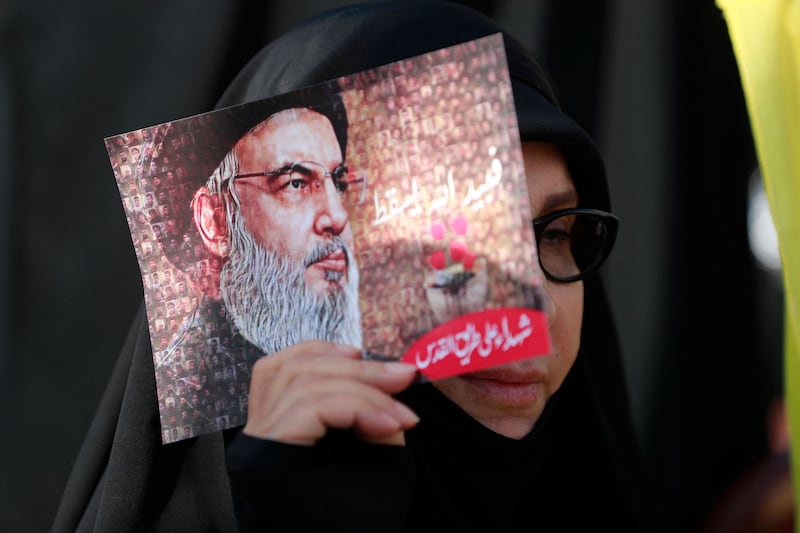 A woman holds up an image of Mr Nasrallah at a pro-Hezbollah rally in southern Beirut.  AFP