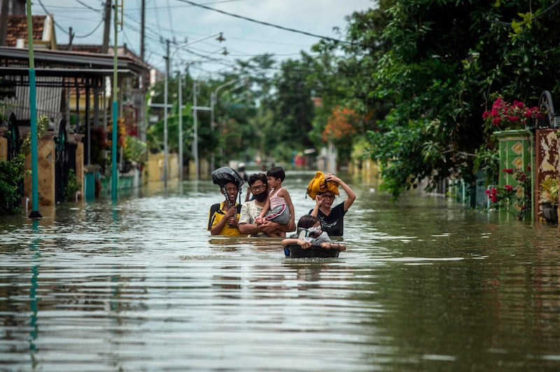 Residents evacuate their flooded homes in Gresik, East Java on December 15, 2020, as the rainy season brings floods to many areas in Jakarta and Java.AFP