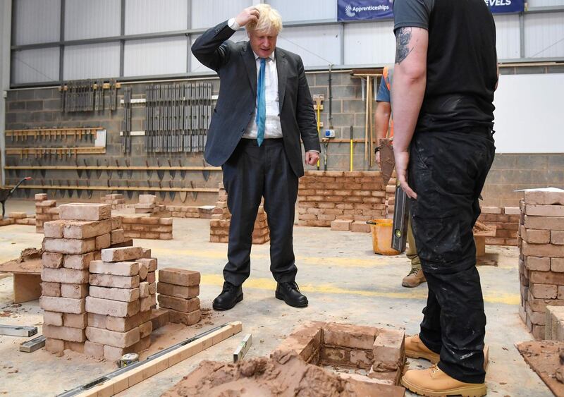 Britain's Prime Minister Boris Johnson reacts as lays bricks whilst talking with students during his visit to Exeter College in Exeter, southwest England on September 29, 2020. / AFP / POOL / Finnbarr Webster
