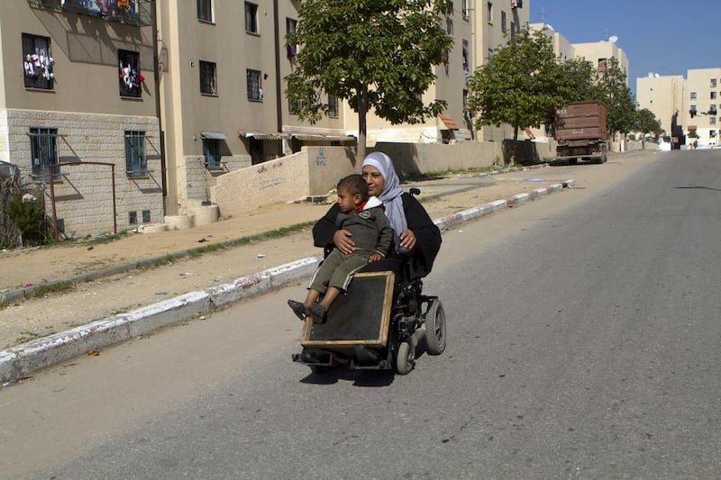 Somah Harp,42, and her son Selman,3, travel towards a market on one of the roads inside Sheikh Zayed City. She says her family depends on UNRWA for most of their food.The Sheik Zayed City charity housing project was ordered and financed  by the late President  of the UAE , Sheikh Zayed bin Sultan Al Nahyan. Photo by Heidi Levine for The National).