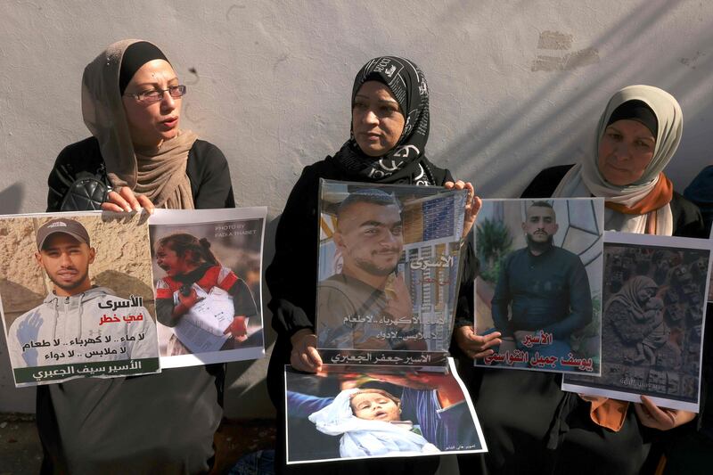 Palestinians hold images of family members outside the Red Cross offices in Hebron, calling for humanitarian access to Palestinians in Israeli jails. AFP