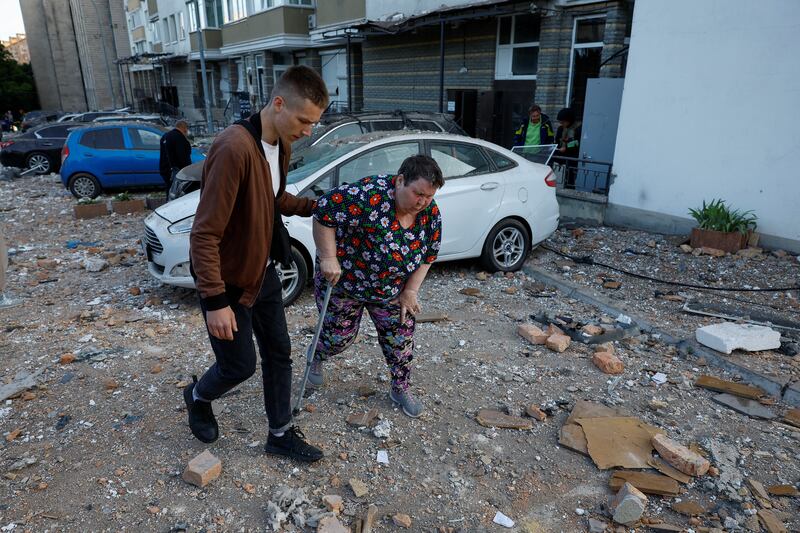 A volunteer helps a woman from an apartment building. Reuters