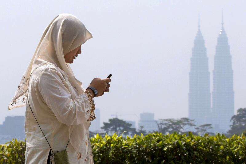 1st: Malaysia. A woman checks her mobile phone as she walks past Malaysia’s landmark Petronas Twin Towers in Kuala Lumpur. Mark Baker / AP Photo