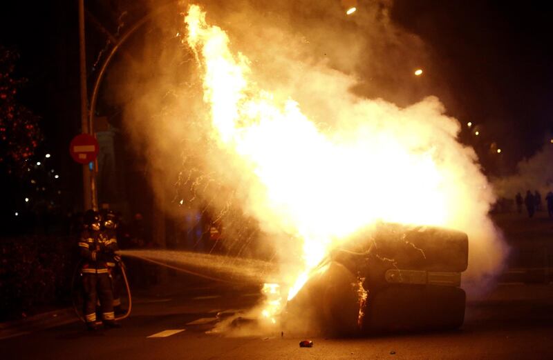 A firefighter puts out a  fire on a dumpster set ablaze during the febrile protests. EPA