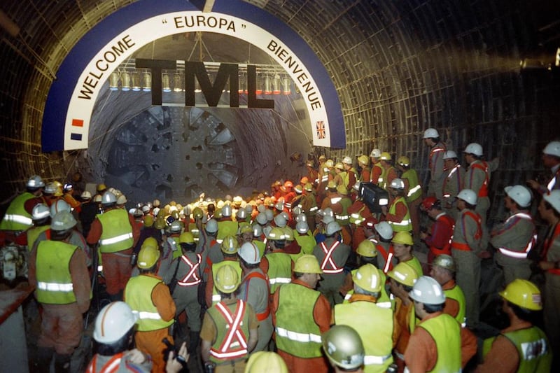 French and British workers look at the tunnel-boring machine Europa during the link-up in the north gallery of the Channel Tunnel on May 22, 1991. / AFP