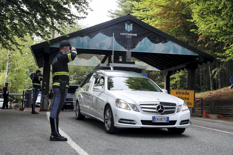 A police officer salutes as a hearse passes by, on the road leading to the Stresa-Mottarone after a cable car of the line collapsed, near Stresa, Italy, Sunday, May 23, 2021. A cable car taking visitors to a mountaintop view of some of northern Italy's most picturesque lakes plummeted to the ground Sunday and then tumbled down the slope, killing at least 13 people and sending two children to the hospital, authorities said. (AP Photo/Antonio Calanni)