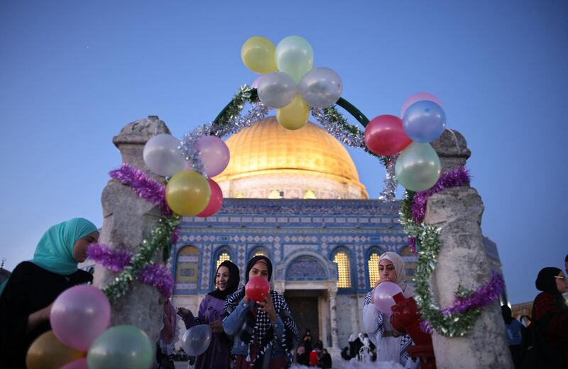 Women blow up balloons as worshippers celebrate Eid al-Fitr holiday after the morning prayer at the Al-Aqsa mosque compound in Old Jerusalem. AFP