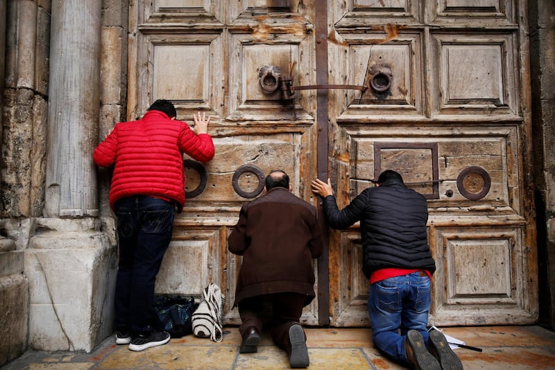 Worshippers kneel and pray in front of the closed doors of the Church of the Holy Sepulchre in Jerusalem's Old City, February 25, 2018. REUTERS/Amir Cohen
