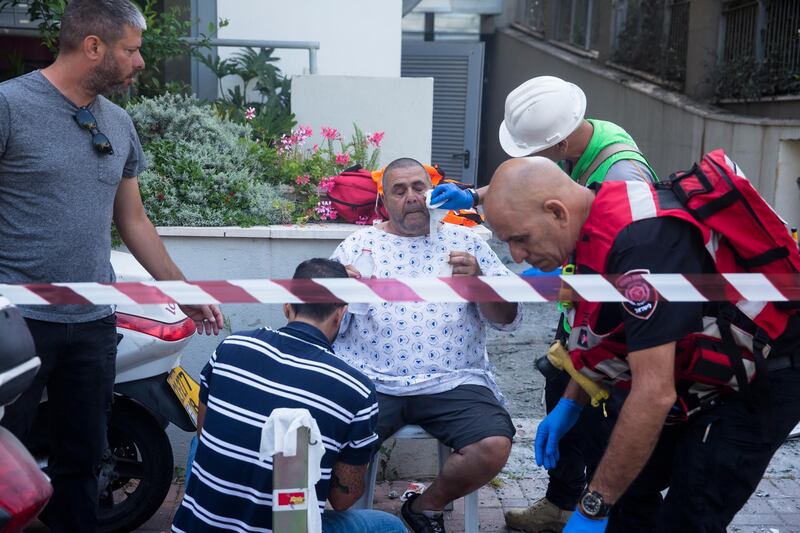 An injured man receives treatment at the scene after a rocket launched from the Gaza strip struck in Giv'atayim, Israel. Getty