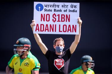 Australia's captain Aaron Finch (L) and teammate David Warner watch as a protester holds a sign as he stands on the field during the one-day international cricket match between India and Australia at the Sydney Cricket Ground (SCG) on November 27, 2020. --IMAGE RESTRICTED TO EDITORIAL USE - NO COMMERCIAL USE-- / AFP / DAVID GRAY / --IMAGE RESTRICTED TO EDITORIAL USE - NO COMMERCIAL USE--