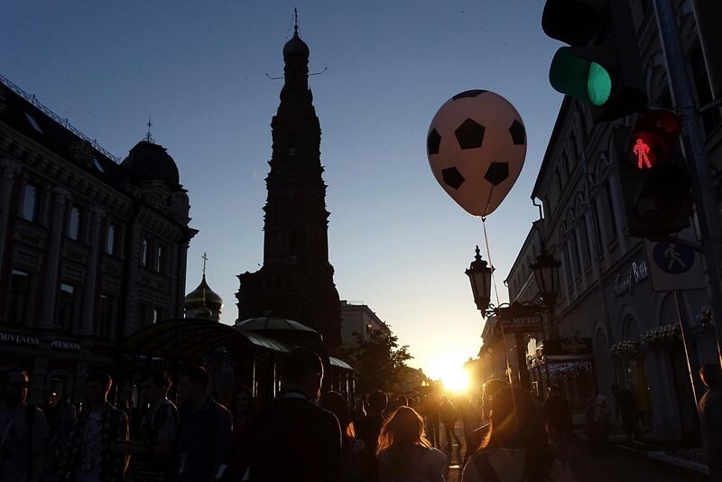 A pedestrian carrying a balloon depicting a football walks at Bauman Street in Kazan, Russia. Eugene Hoshiko / AP Photo
