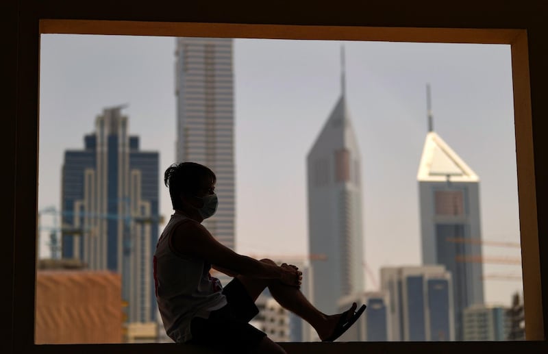A man wearing a face mask gazes at the Dubai skyline from a window on April 5, 2020. AFP