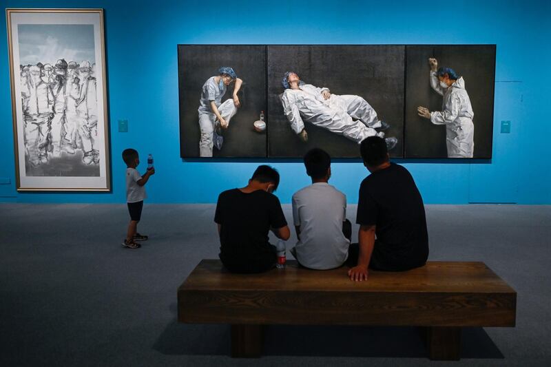 People visit the art exhibition 'Unity is strength: An art exhibition on the fight against Covid-19', which includes 'Eternity and Brevity', right, by artist Pang Maokun, on the fight against the coronavirus at the National Museum of China in Beijing. AFP