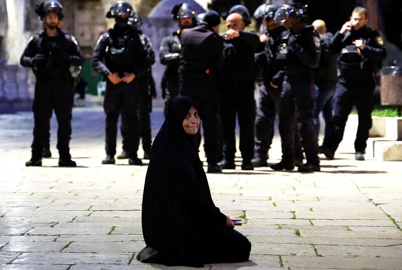 A Palestinian woman sits near Israeli border policemen in Al Aqsa Mosque compound, also known to Jews as the Temple Mount, while tension arises during clashes with Palestinians in Jerusalem's Old City. Reuters