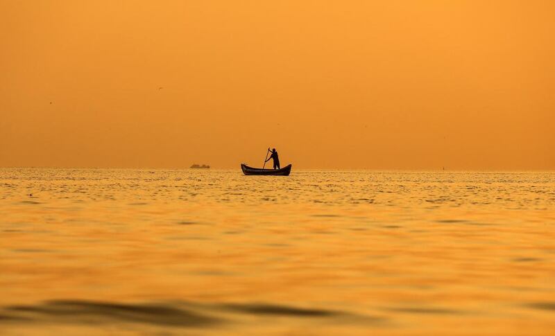 As the sun sets a fishermen paddles his boat along the Arabian Sea coast of Mumbai.  Divyakant Solanki / EPA