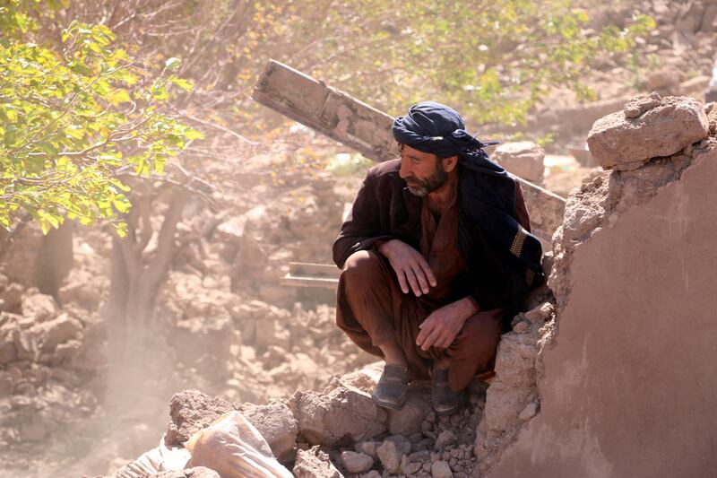 An Afghan man sits in the courtyard of his destroyed home. AP