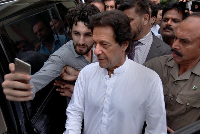 A Pakistani takes selfie with Imran Khan, center, head of the Pakistan Tehreek-e-Insaf party, as he leaves a party meeting in Islamabad, Pakistan, Monday, Aug. 6, 2018. The party won the most parliament seats in last month's general elections and is expected to form a governing coalition later this month. (AP Photo/Anjum Naveed)