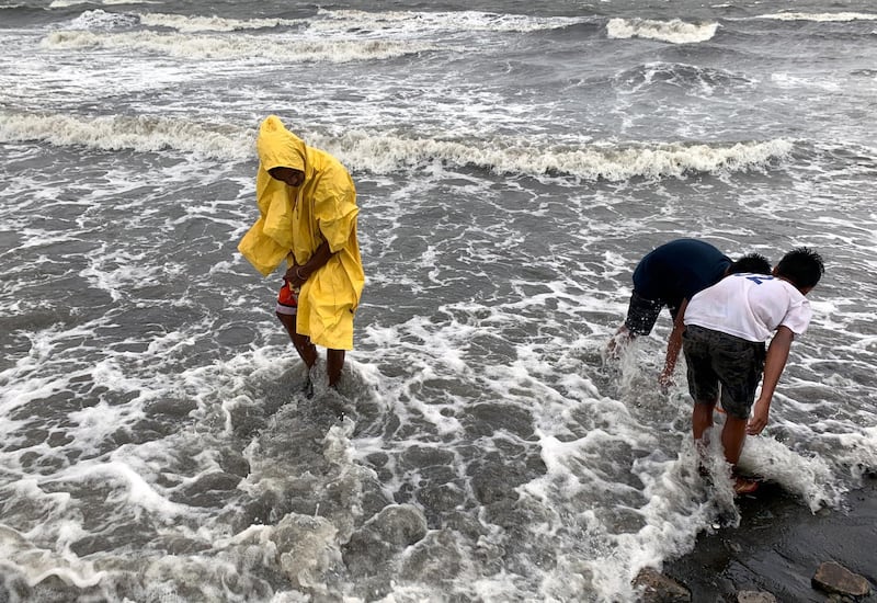 Villagers collect shells during strong winds brought by Typhoon Kammuri, in Cavite City.  EPA