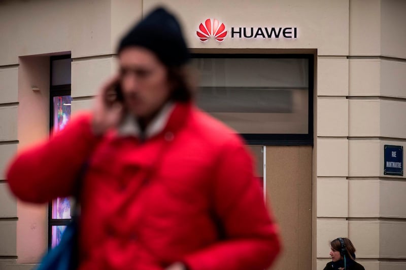 People pass by a Huawei logo above the entrance of a Huawei store in Paris on February 4, 2019.  A government amendment to establish a pre-authorization for the operation of telecom networks, with a view to deploy 5G, received on February 4, 2019 an "unfavorable opinion" from the special commission charged with examining the draft law Pact. / AFP / Lionel BONAVENTURE
