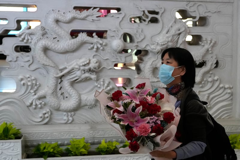 A woman holds a bouquet of flowers upon arriving at the Beijing Capital International Airport in Beijing, on Tuesday. AP