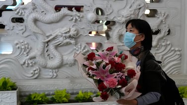 A woman holds a bouquet of flowers upon arriving at the Beijing Capital International Airport in Beijing, on Tuesday. AP